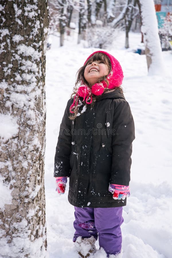 Little girl in jacket and knitted hat catching snowflakes in winter park on Christmas. stock photo Little girl in jacket and knitted hat catching snowflakes in winter park on Christmas. stock photo
