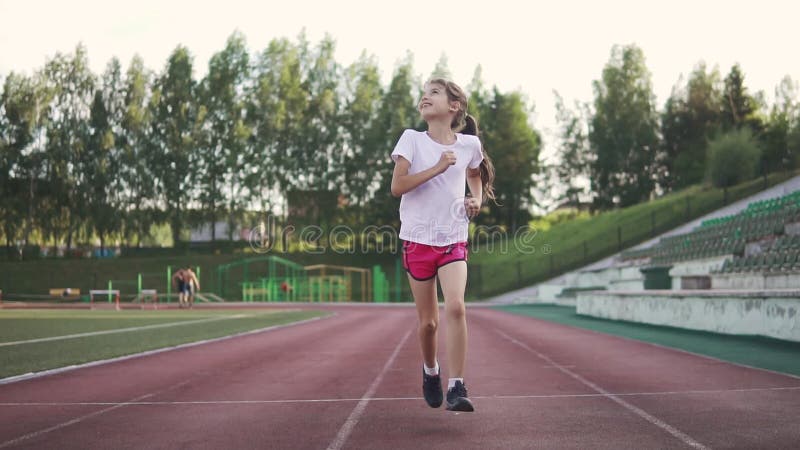 Little girl jogging in the stadium. the child goes in for sports in the open air. children`s sport.