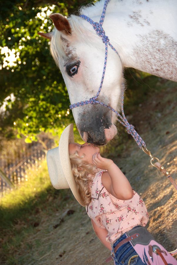 Little girl kissing pony.