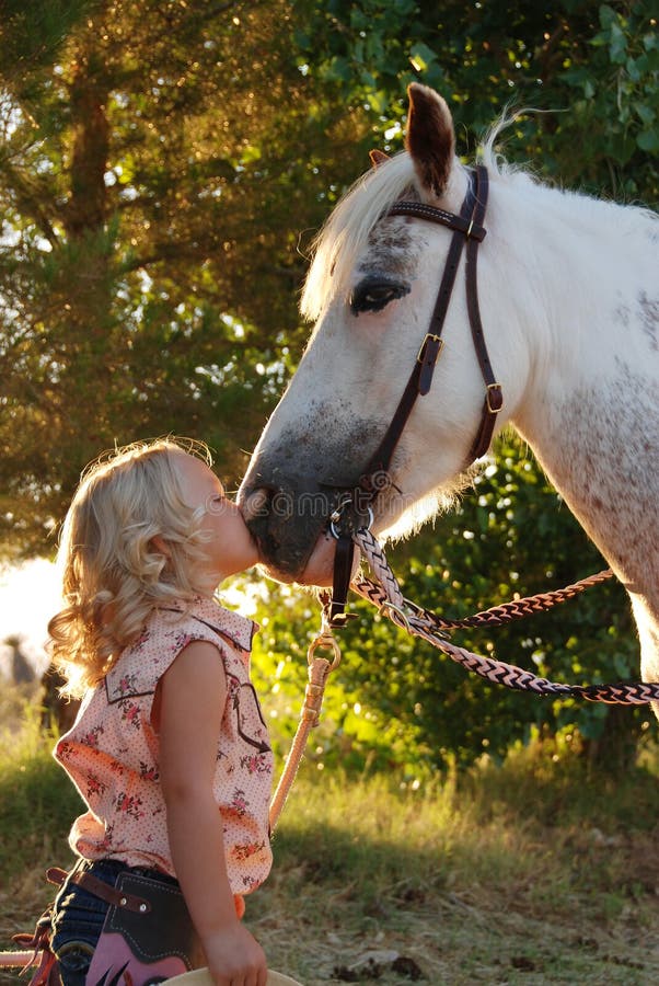 Little girl kissing pony.