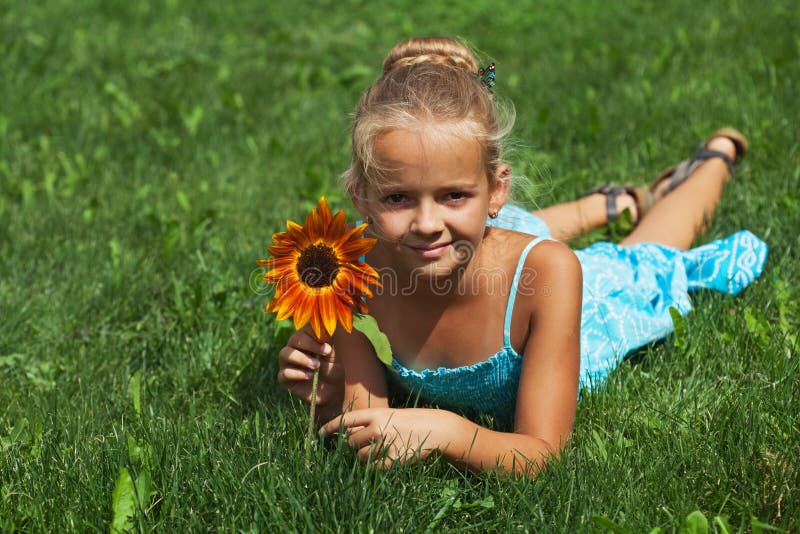 Little girl laying on the grass with a flower