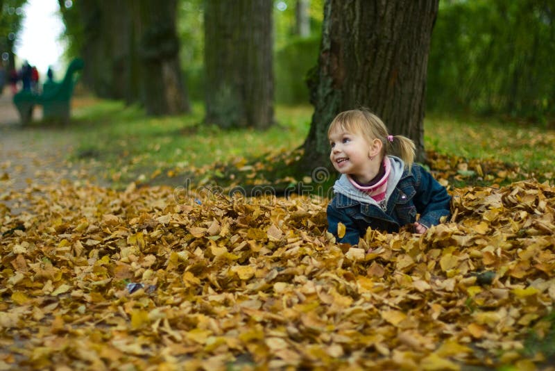 Little girl lies at yellow leaves