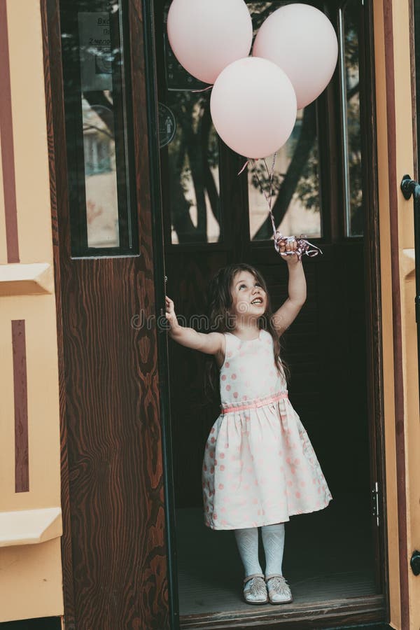 A Little Girl with Long Hair in a Pink Dress Gets Out of the Tram with  Balloons in Her Hands Stock Photo - Image of happiness, happy: 226943842