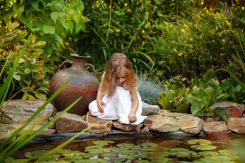 Little girl looking into a pond with lilies