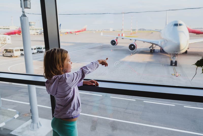 Little girl is looking to airplanes in airport waiting lounge in Moscow