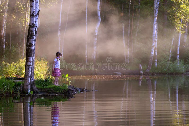 Little girl looks at beautiful lake with steam above water