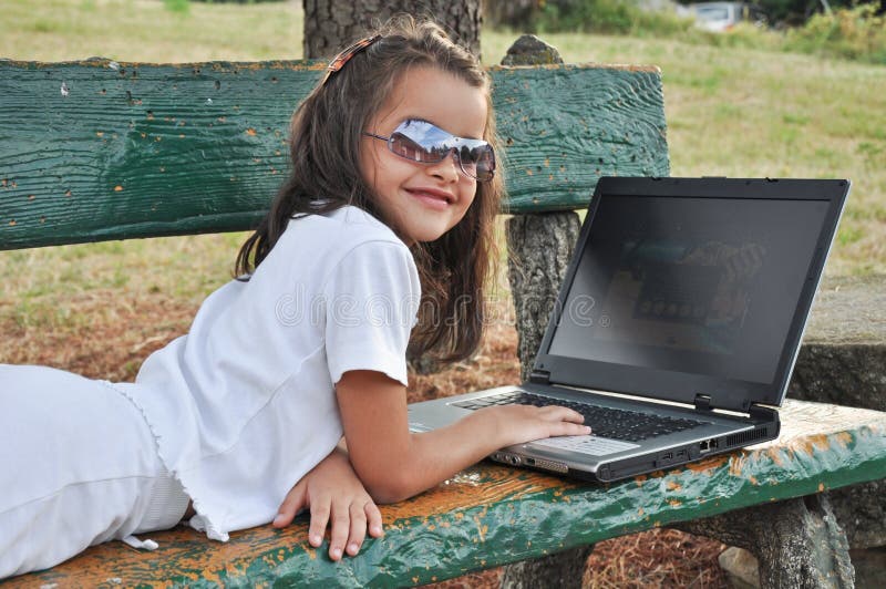 Little girl lying on a bench with your computer