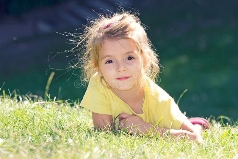 Little girl lying on the green grass.Child outdoor closeup face