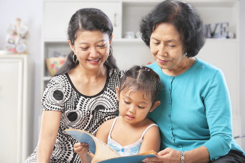 Pequeno asiático acompanado de acuerdo a su madre a abuela lectura un libro.