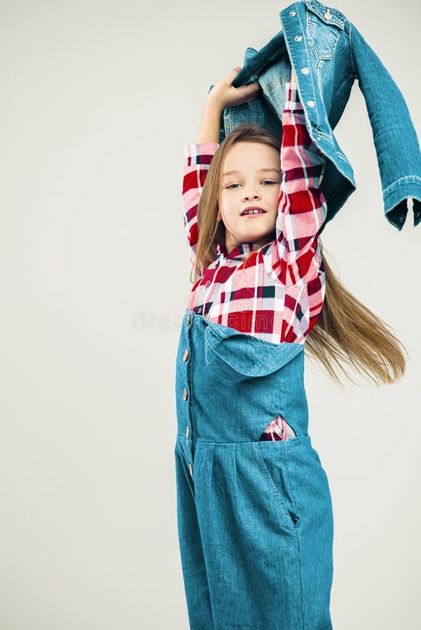 Little girl in motion. child with air hairstyle. Kid in denim suit and plaid shirt posing in the studio. fashion photography stock images Little girl in motion. child with air hairstyle. Kid in denim suit and plaid shirt posing in the studio. fashion photography stock images