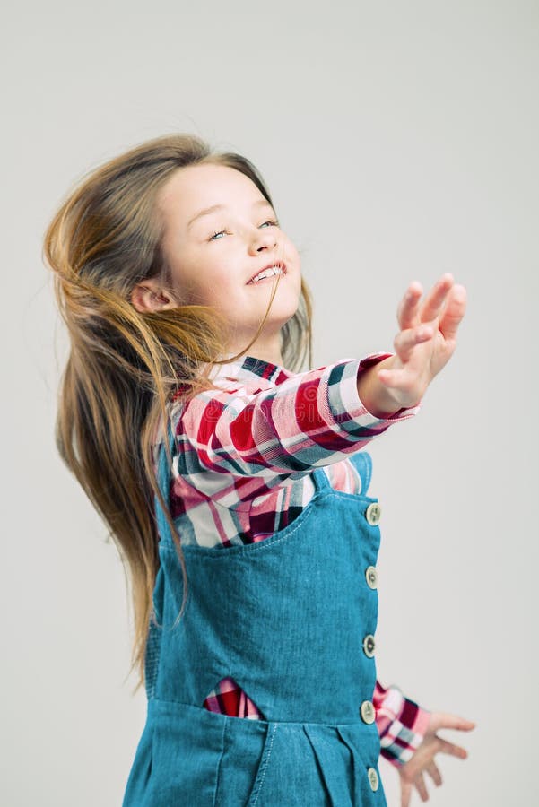 Little girl in motion. child with air hairstyle. Kid in denim suit and plaid shirt posing in the studio. fashion photography stock images Little girl in motion. child with air hairstyle. Kid in denim suit and plaid shirt posing in the studio. fashion photography stock images