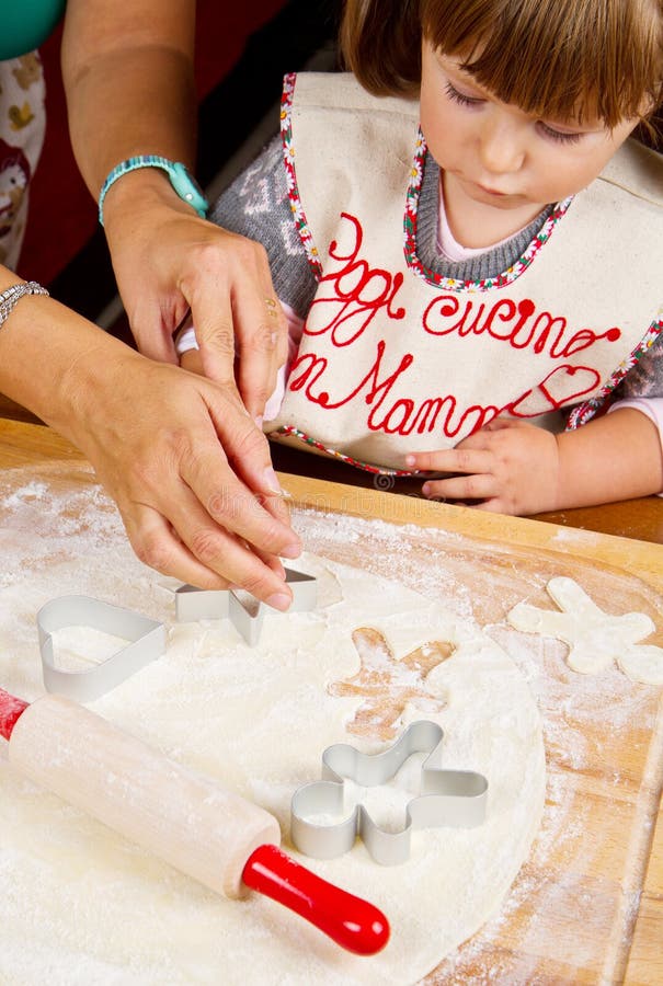 Little girl with mum baking Christmas cookies stock images