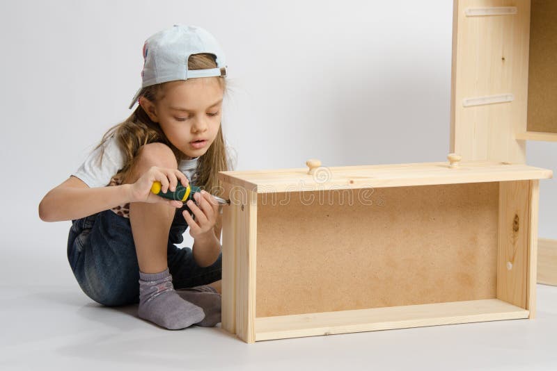 Little girl in overalls collector of furniture making box on the dresser royalty free stock image Little girl in overalls collector of furniture making box on the dresser royalty free stock image