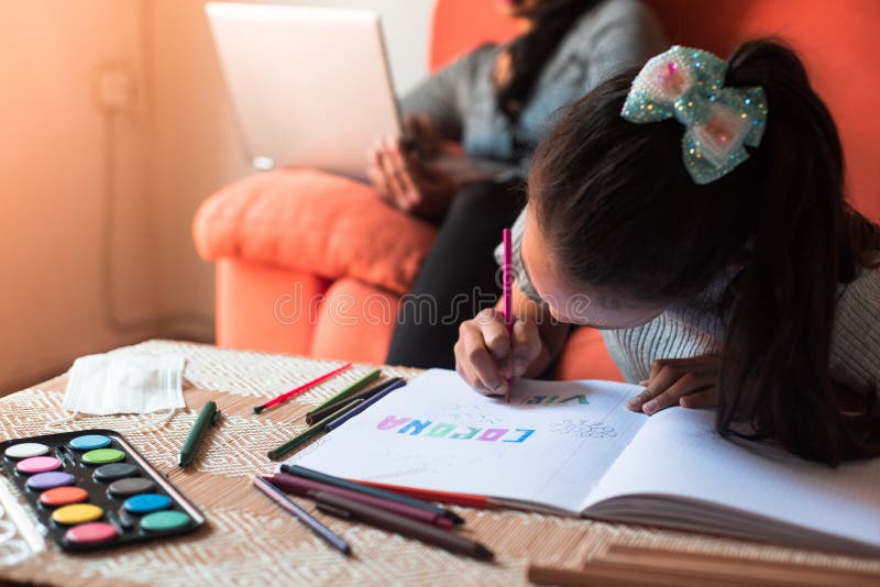 Little girl painting on the notebook at the table while her mother are working at the laptop sitting on the sofa on the living royalty free stock images Little girl painting on the notebook at the table while her mother are working at the laptop sitting on the sofa on the living royalty free stock images