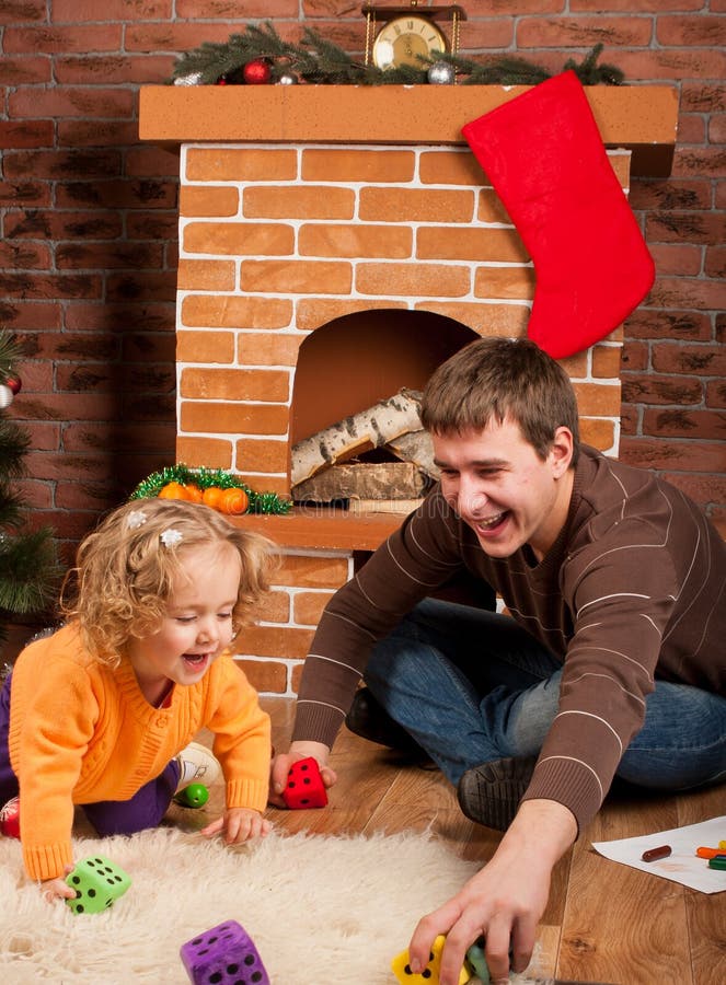 Little girl play with dad near Christmas tree