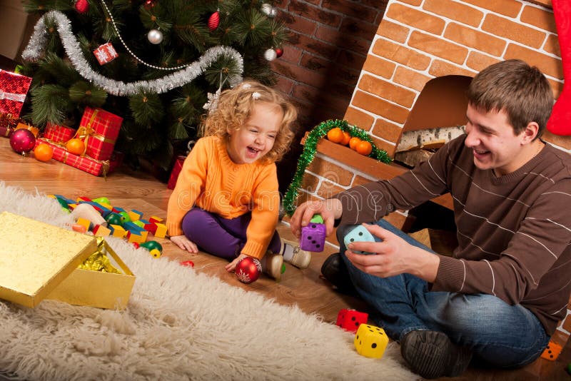 Little girl play with dad near Christmas tree