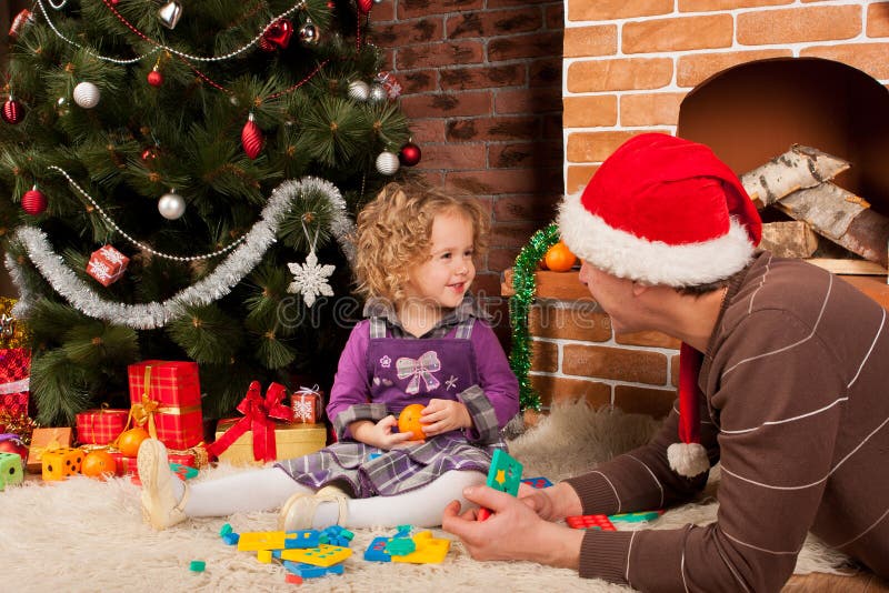 Little girl play with dad near Christmas tree