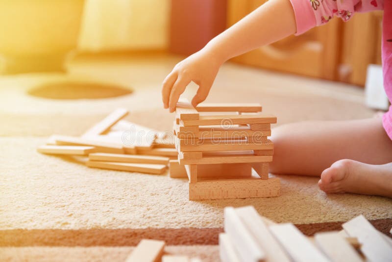 Little girl play game on carpet and builds tower, development toys, light effect