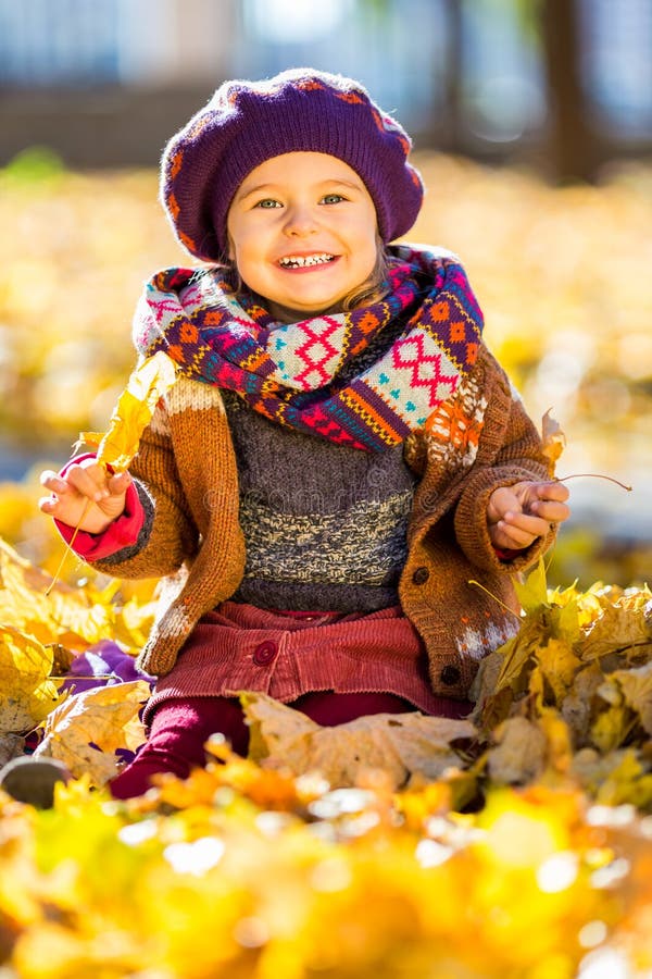 Little girl playing with autumn leaves