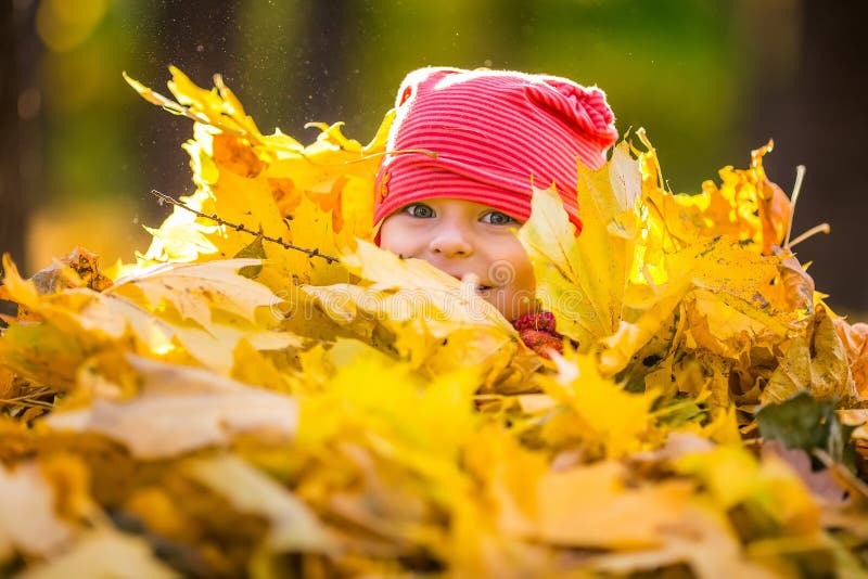 Little girl playing with autumn leaves