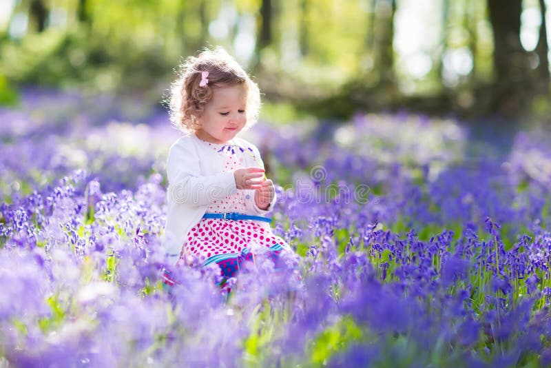 Little girl playing in bluebell flowers field
