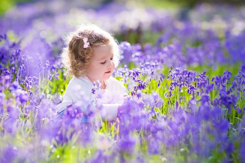 Little girl playing in bluebell flowers field