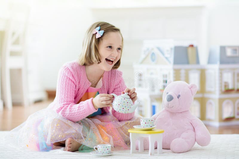 Little girl playing with doll house. Kid with toys