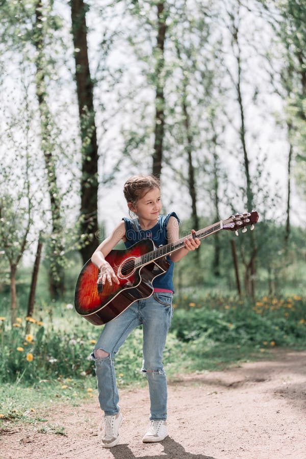 Little girl playing guitar standing on the path in the city Park royalty free stock photo Little girl playing guitar standing on the path in the city Park royalty free stock photo