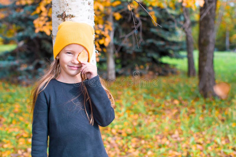 Little girl playing hide and seek in autumn forest outdoors. Little girl playing hide and seek in autumn forest outdoors