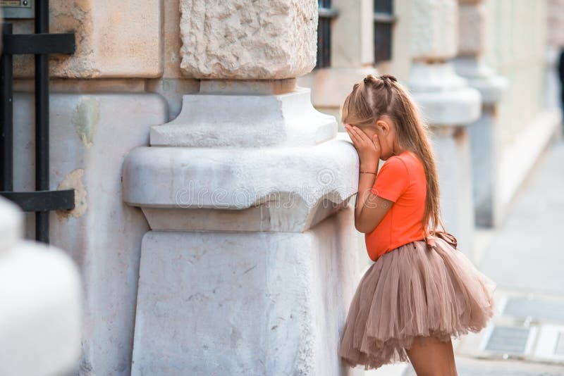Little girl playing hide and seek on street in Europe outdoors