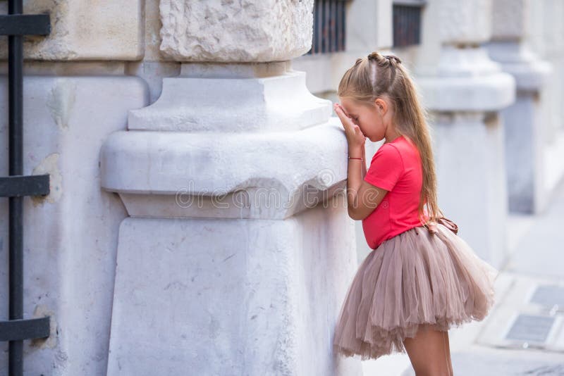 Little fashion girl playing hide and seek on street in Paris outdoors