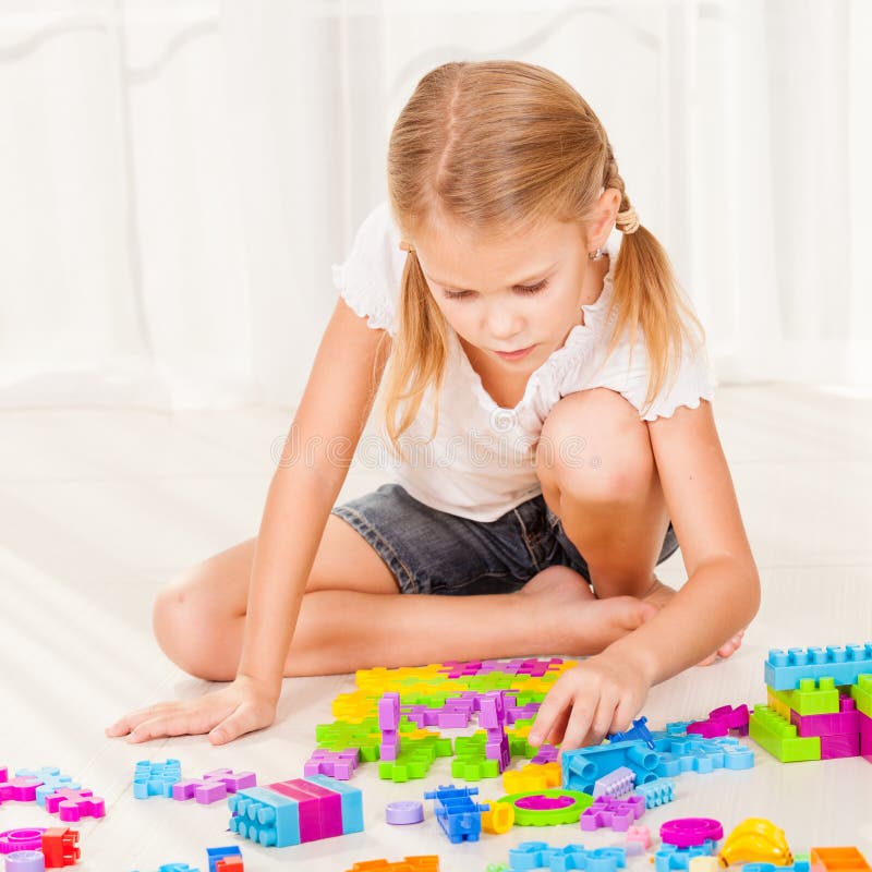 Little girl playing Lego on the floor