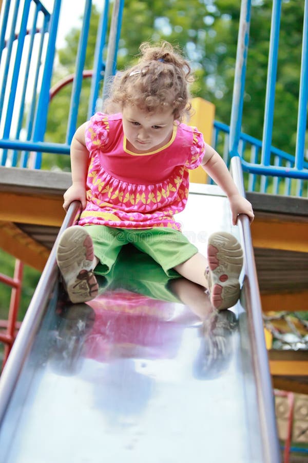 Little girl playing on a playground slide.