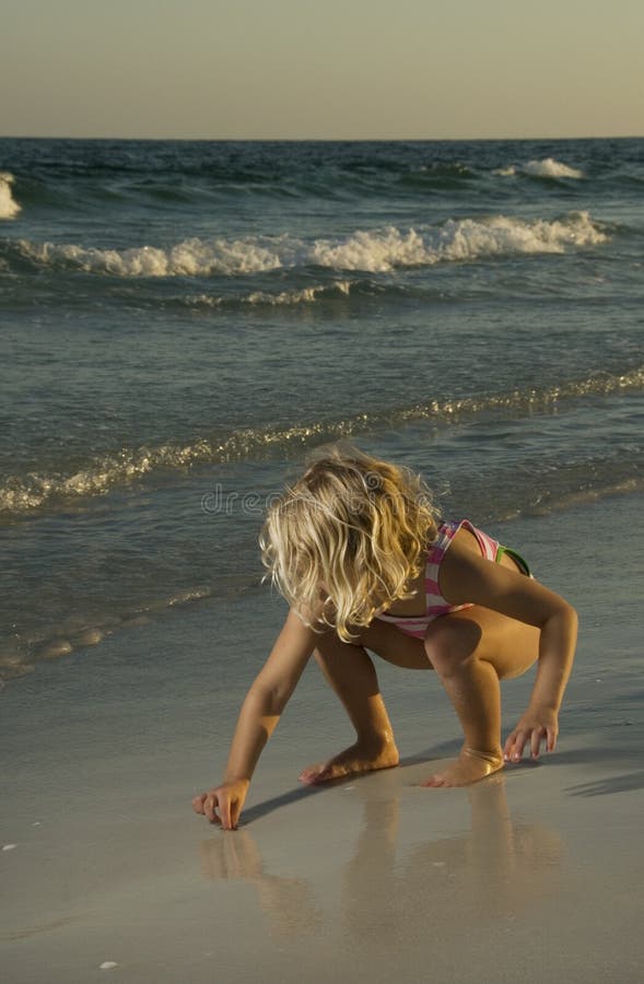 Little girl playing in sand at beach royalty free stock photo