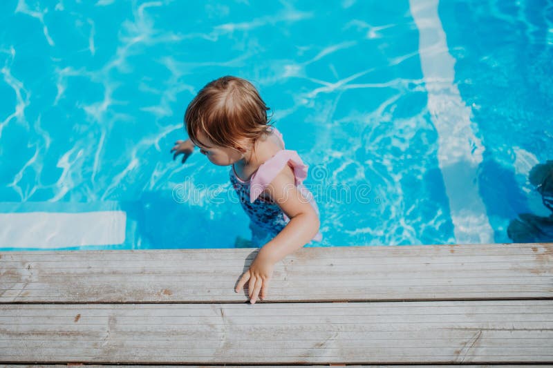 Little girl playing in shallow water in pool. stock images