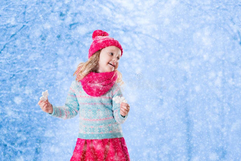 Little girl playing with toy snow flakes in winter park