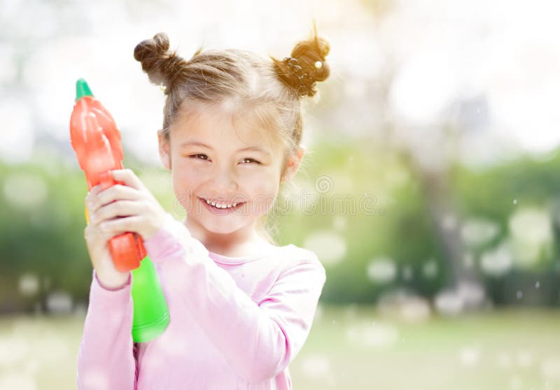 Little girl playing water guns in the park