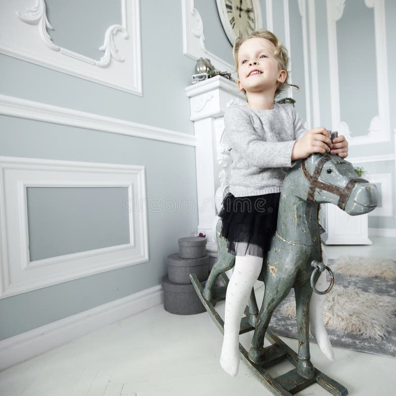 Little girl playing with a wooden horse royalty free stock image Little girl playing with a wooden horse royalty free stock image