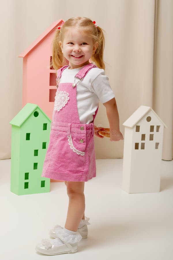 Little girl is playing with wooden houses.