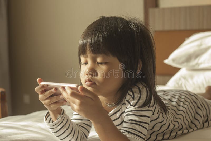 Little Girl Plays with Gadget Smart Phone stock photo