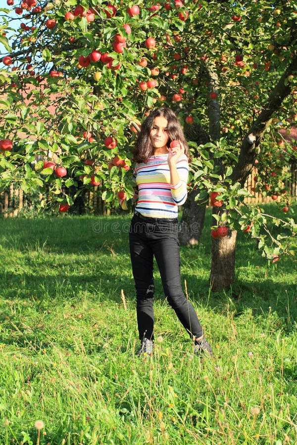 Girl under apple tree holding apple