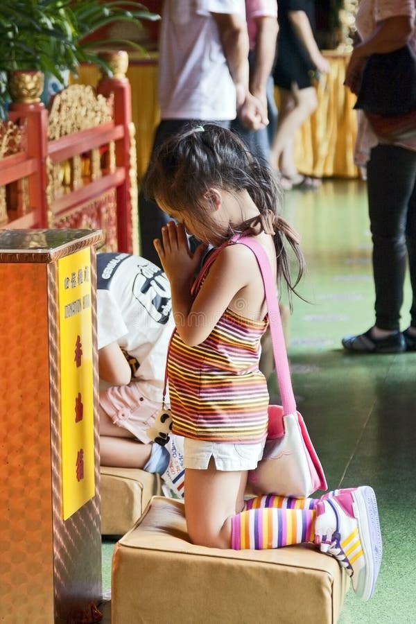 A little girl dressed in colorful clothes kneels for prayer at a Buddhist temple in the Big Buddha complex in Hong Kong. A little girl dressed in colorful clothes kneels for prayer at a Buddhist temple in the Big Buddha complex in Hong Kong.