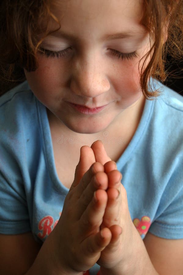 A young little girl with her hands closedin prayer. A young little girl with her hands closedin prayer.
