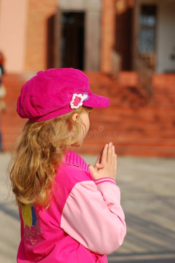 Little girl praying with hands together in front of church. Little girl praying with hands together in front of church