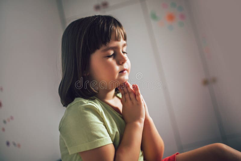 Little girl praying at home. Cute little girl praying at home