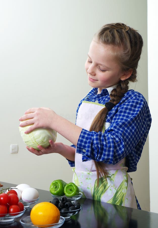 Little girl is preparing vegetables for salad closeup