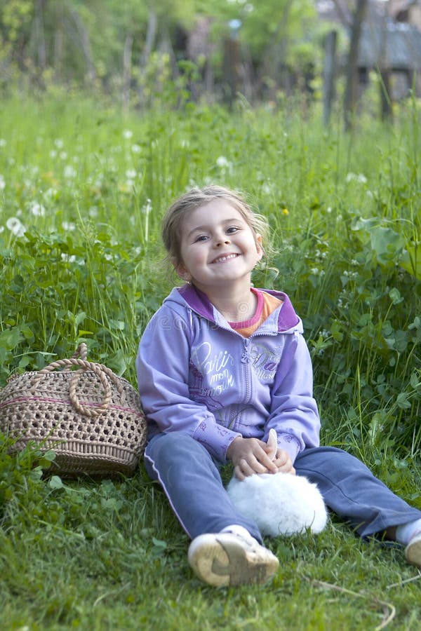 Little girl with rabbit on grass