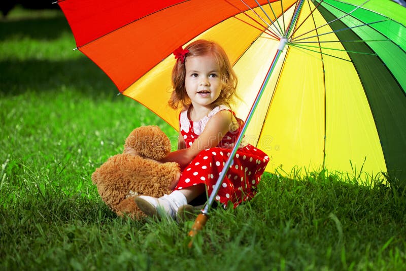 Little girl with a rainbow umbrella in park