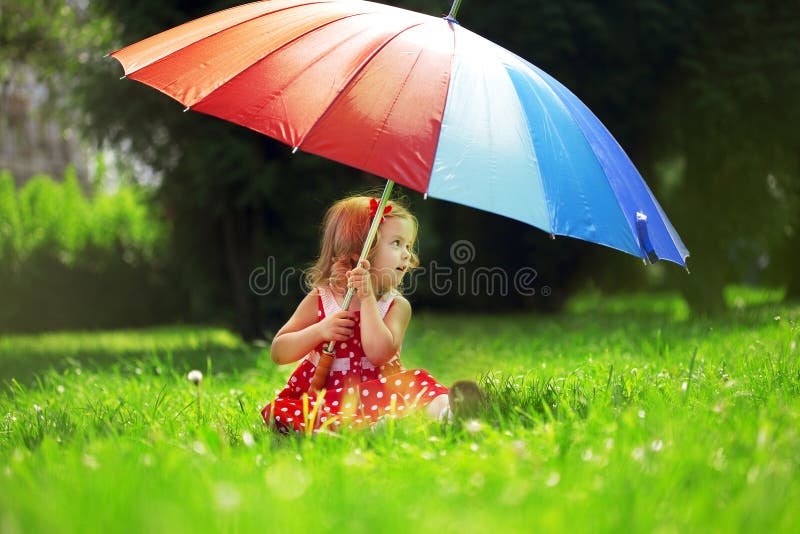 Little girl with a rainbow umbrella in park