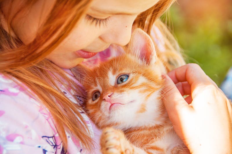 Little girl with a red kitten in hands close up. Bestfriends. I